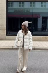 a lady in a white down jacket and a pair of beige pants